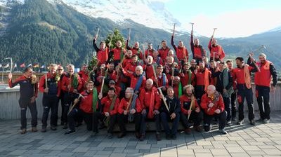 Gruppe von Menschen in roten Jacken mit Eispickeln vor Bergkulisse.