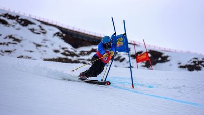 Skier with helmet and ski poles slaloms on a snow-covered mountain.
