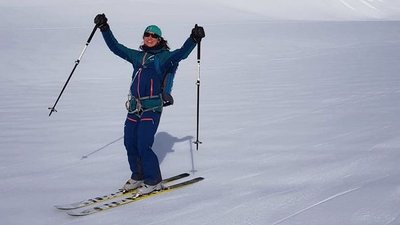 Person on skis with poles and helmet in a snow-covered mountain landscape.