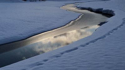 Snow-covered landscape with a narrow river winding through the terrain.