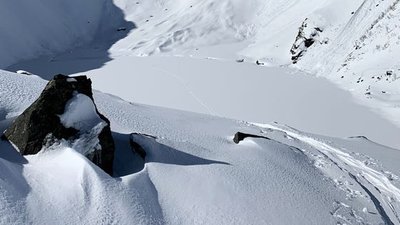 Snow-covered mountain landscape with rocks and ski tracks, surrounded by snow-covered slopes.