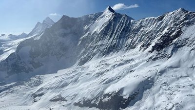 Snow-covered mountain landscape in the Alps with steep peaks and clear sky in the background.