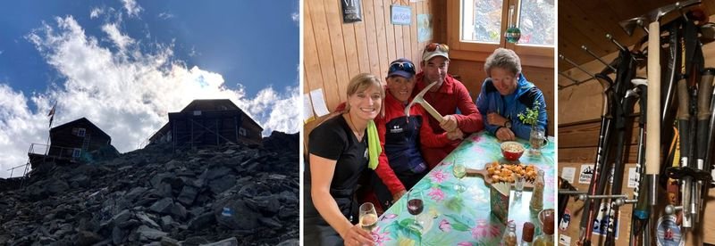 Mountain hut on rocks, four people at a table in the hut, hiking poles on the wall.