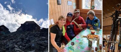 Mountain hut on rocks, four people at a table in the hut, hiking poles on the wall.