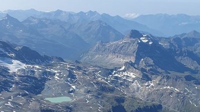Mountain landscape in Switzerland with snow-covered peaks and a turquoise lake in the valley.