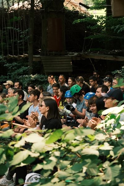Gruppe von Personen mit Kletterhelmen und Outdoor-Kleidung versammelt im Wald vor Klettergerüst und Seilpark.