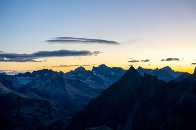 Berglandschaft bei Sonnenaufgang mit dunklen Gipfeln und klarem Himmel, keine Personen oder Ausrüstung sichtbar.