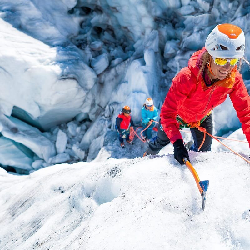 Girl reaches top while ice climbing and smiles