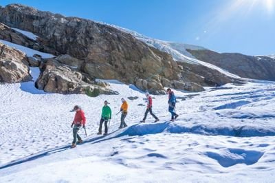 A group of five people is walking across the glacier.