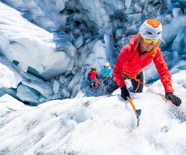Bergsteiger klettert mit Pickel im Eis
