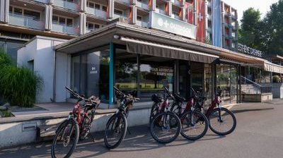 Bicycles parked outside an adventure company building with signage and a multi-story structure behind.