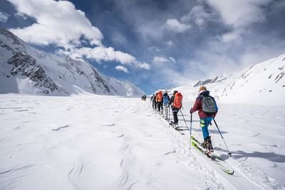 Skitourengängerinnen sind unterwegs auf der Lötschenlücke. Der Himmel ist blau mit etwas Wolken.