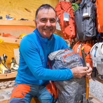 Ein Bergführer zeigt wie man einen Pickel korrekt auf einen Rucksack aufbindet.