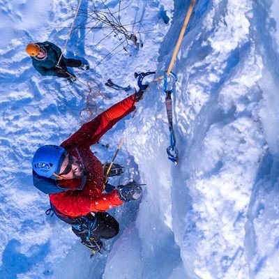 Mädchen erreicht die Spitze beim Eisklettern und lächelt.
