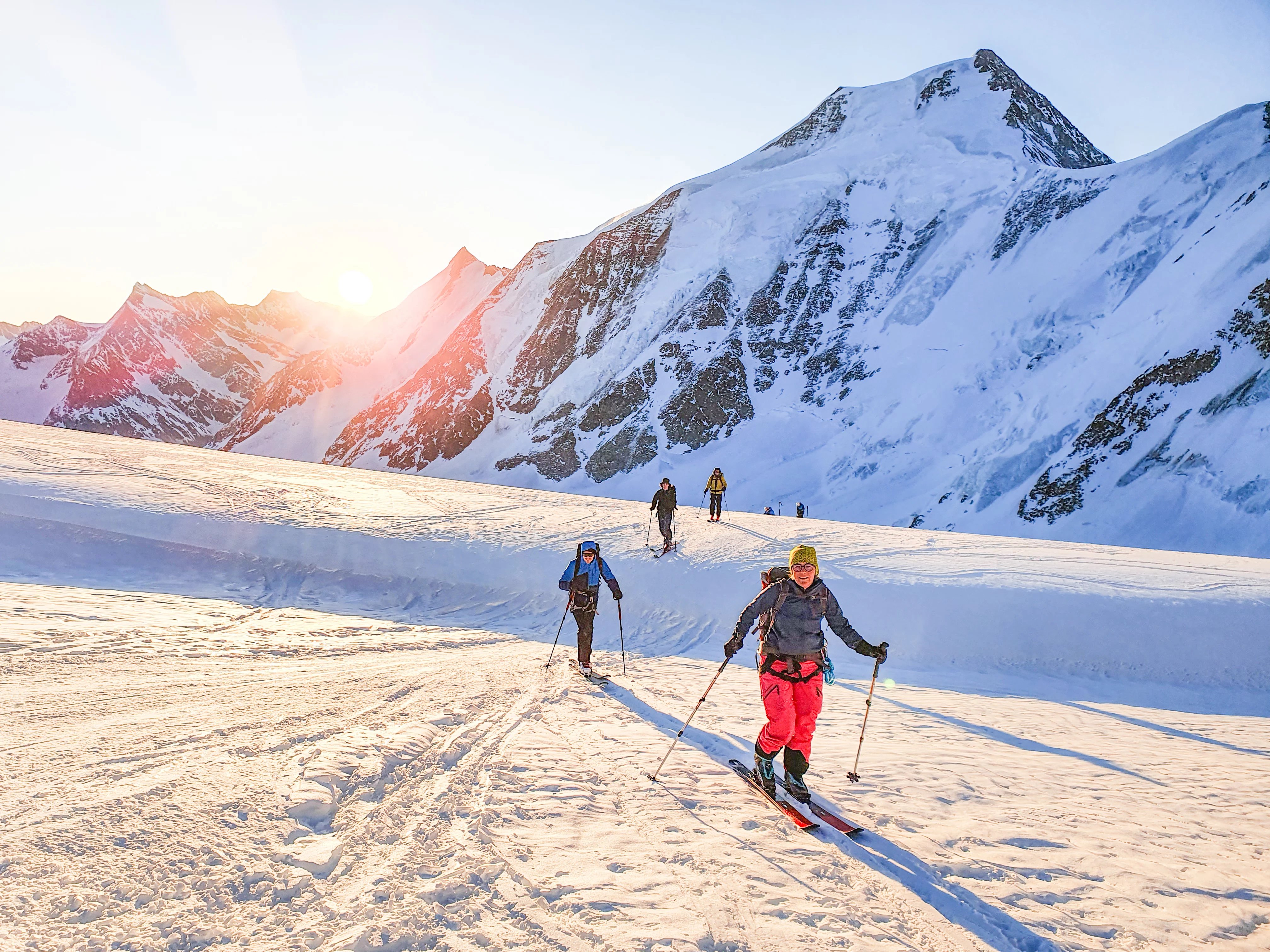 Ski tourers ascending with sunrise in the background