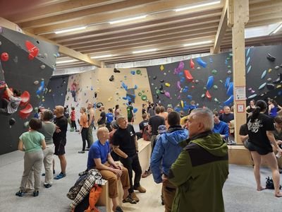 People in an indoor climbing gym with colorful holds on walls, some wearing climbing shoes.