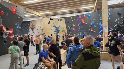People in an indoor climbing gym with colorful holds on walls, some wearing climbing shoes.