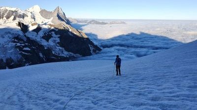 Bergsteiger auf dem Gletscher mit Nebelmeer und Eiger und Mönch im Hintergrund