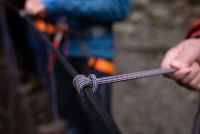 Personen halten Kletterseile mit Knoten, tragen Sicherheitsgurte; im Hintergrund Felsen.