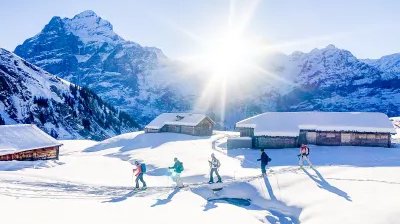 Skitourengänger im Aufstieg bei Alphütten mit dem Wetterhorn im Hintergrund