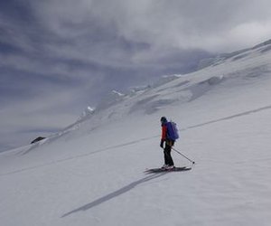 Skitourengänger in der Abfahrt mit Gletscherabbruch im Hintergrund