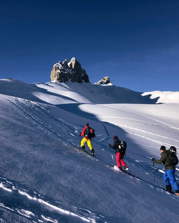 Ski tourers ascending with the Lobhorn mountains in the background.