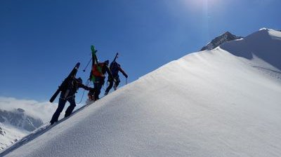 Skitourengänger mit aufgebundenen Ski auf Grat