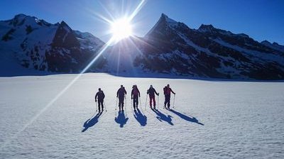 Skitourengänger auf dem Konkordiaplatz mit Sonnenaufgang im Hintergrund