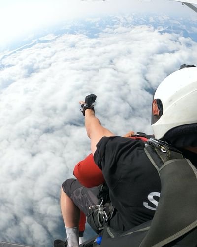 People with helmets and parachutes in an airplane above clouds.