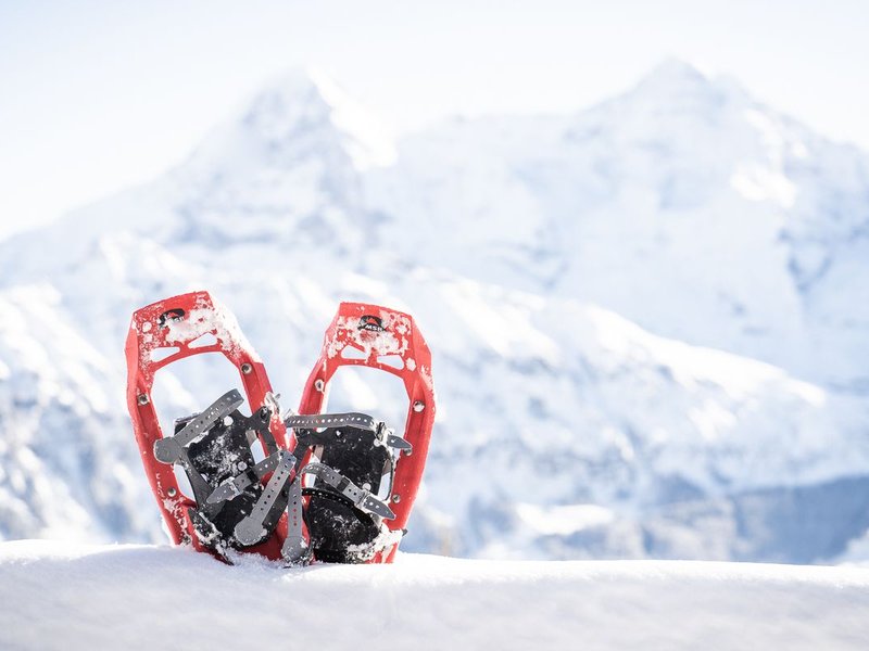 Red snowshoes in the snow in front of snow-covered mountains in Switzerland.