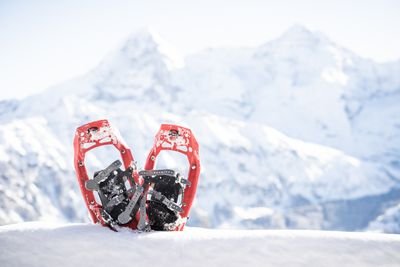 Rote Schneeschuhe im Schnee vor verschneiten Bergen in der Schweiz.