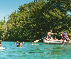 Menschen in der Aare schwimmend neben dem Schlauchbot während der Aare Flussfahrt.