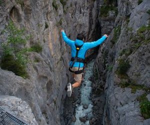 Person in blue jacket securely jumps into the glacier gorge in Grindelwald at the Canyon Swing