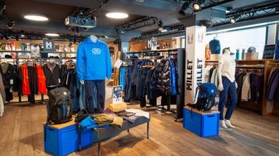 Outdoor-Shop mit Schaufensterpuppen, Jacken, Rucksäcken, Markenregalen (Millet) und Holzfußboden