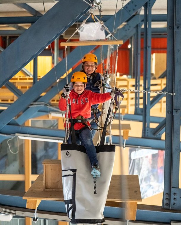 Two people happily overcome an obstacle at the Indoor Rope Park Grindelwald
