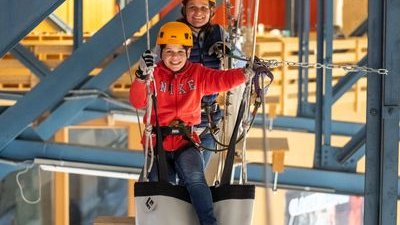 Two people happily overcome an obstacle at the Indoor Rope Park Grindelwald