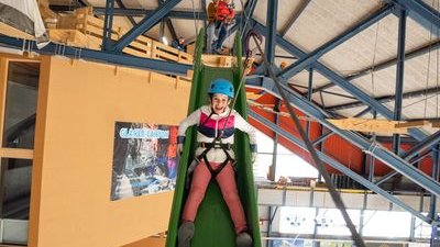 Child slides down a green slide at the Indoor Rope Park Grindelwald