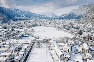 Verschneite Stadtansicht mit Bergen im Hintergrund, Gebäude und Straßen bedeckt von Schnee.