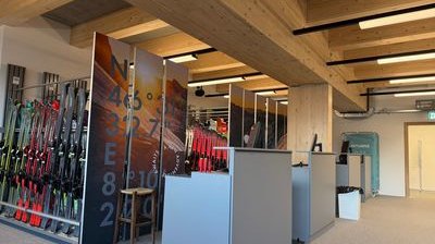 Ski rental with shelves full of ski equipment, wooden beam ceiling, and modern reception desk.
