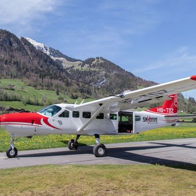 Ein rotes und weißes Flugzeug steht auf einer Landebahn vor einer Berglandschaft.